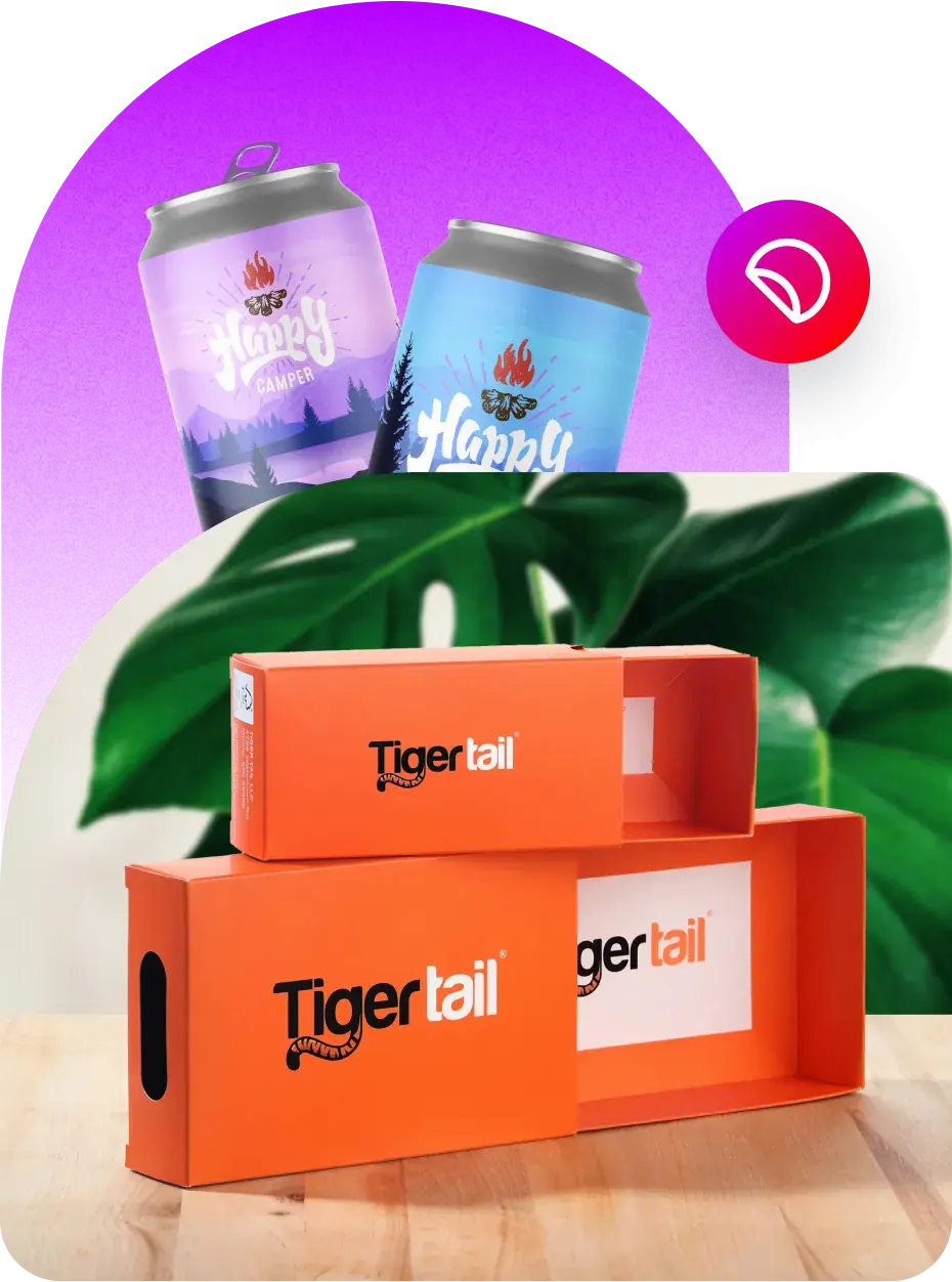 Two colorful beverage cans with 'Happy Camper' branding, one in purple and the other in blue, placed against a gradient purple background. Below the cans are two orange rectangular boxes with 'Tigertail' branding, positioned on a wooden surface. A large green leaf is partially visible behind the boxes.